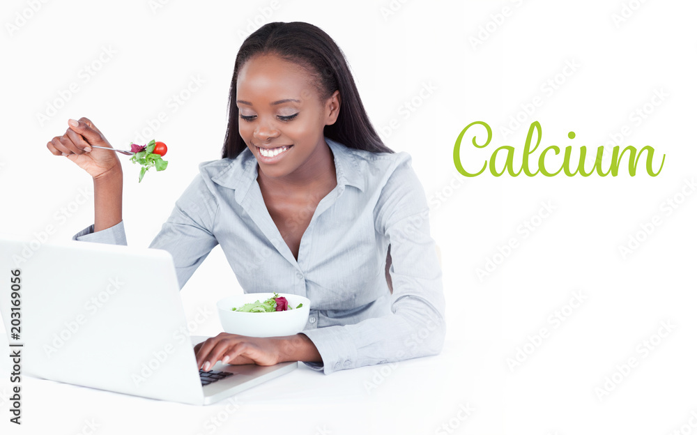 The word calcium against young businesswoman working with a notebook while eating a salad