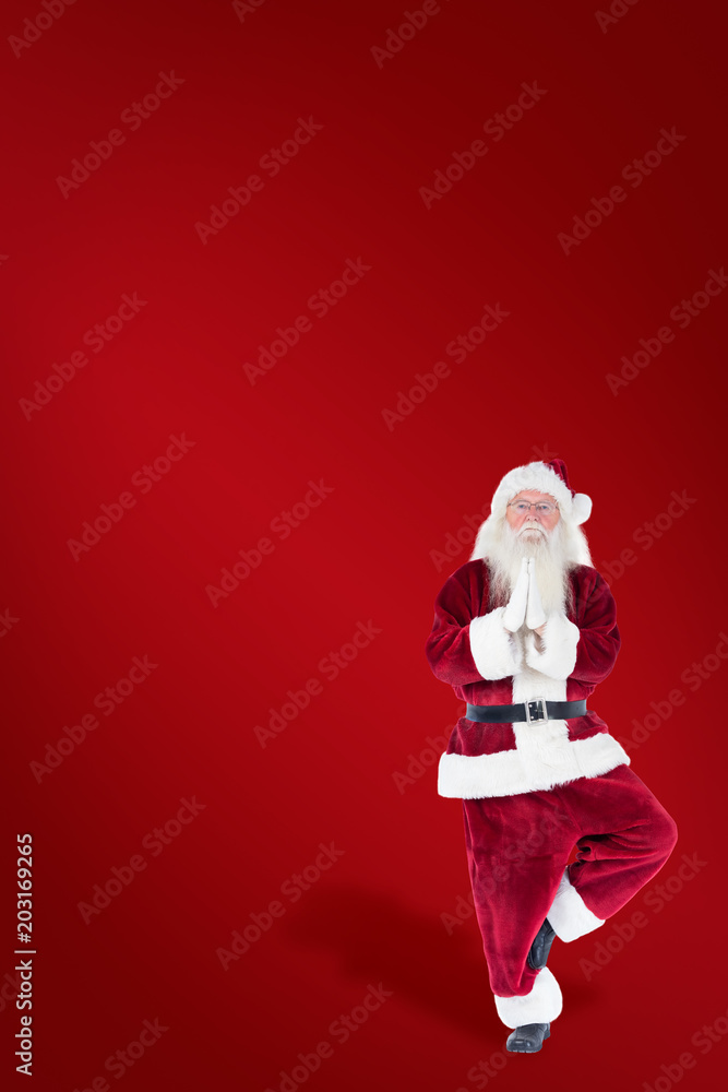 Father Christmas doing some yoga against red background