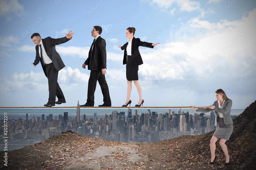 Young businesswoman pulling a tightrope for business people against large city on the horizon