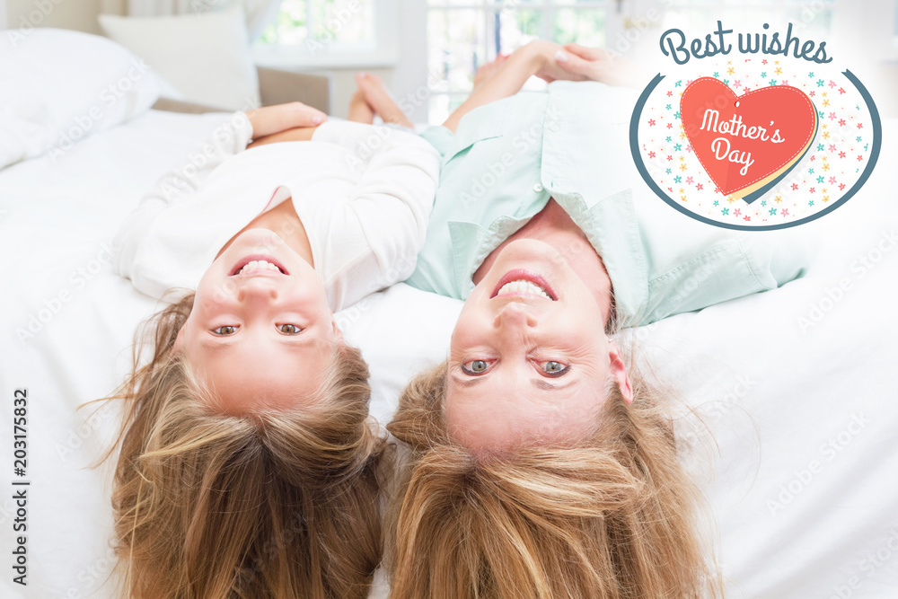 mothers day greeting against mother and daughter looking at camera lying on the bed 