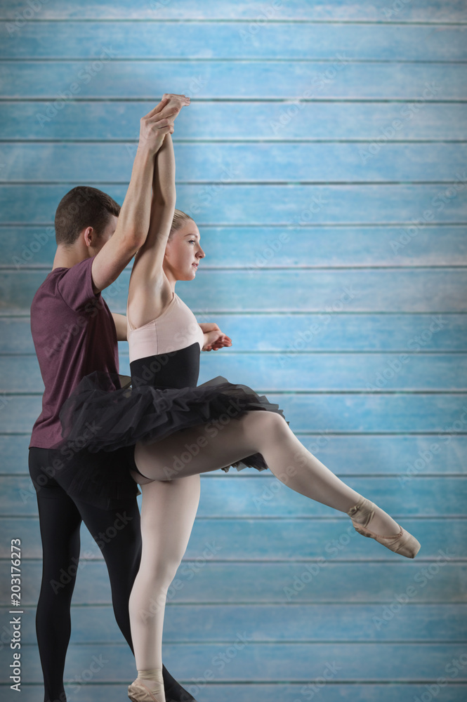 Ballet partners dancing against wooden planks