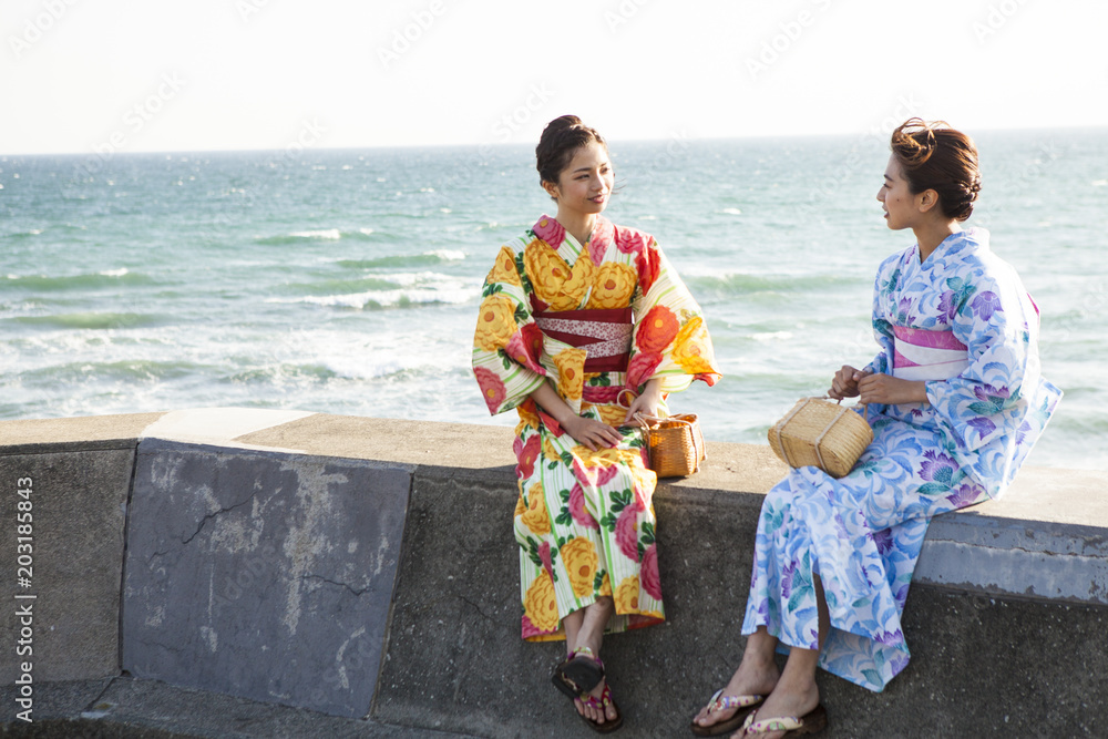 海辺でおしゃべりしている浴衣女性たち