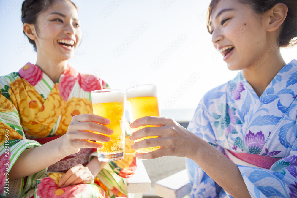 浴衣を着た女性たちは生ビールで乾杯している