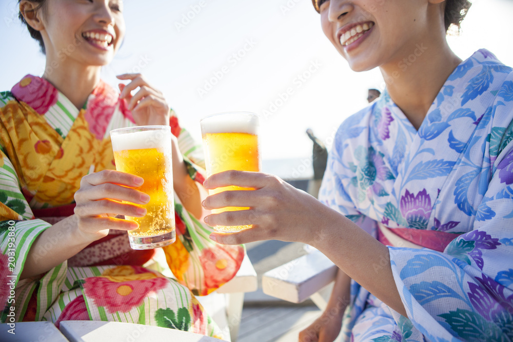 浴衣を着た女性たちは生ビールで乾杯している