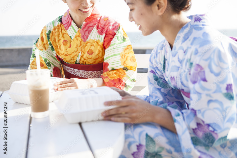 浴衣女性たちは海辺で休憩している