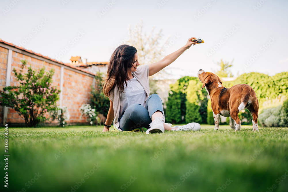 Young woman giving a treat to her dog in the garden.