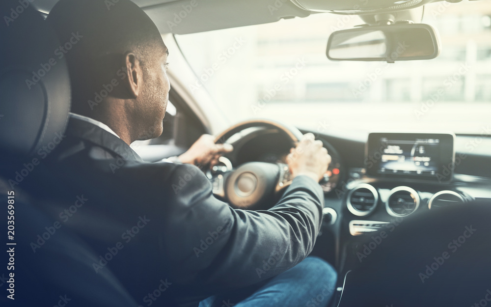 Young African man driving a car through the city