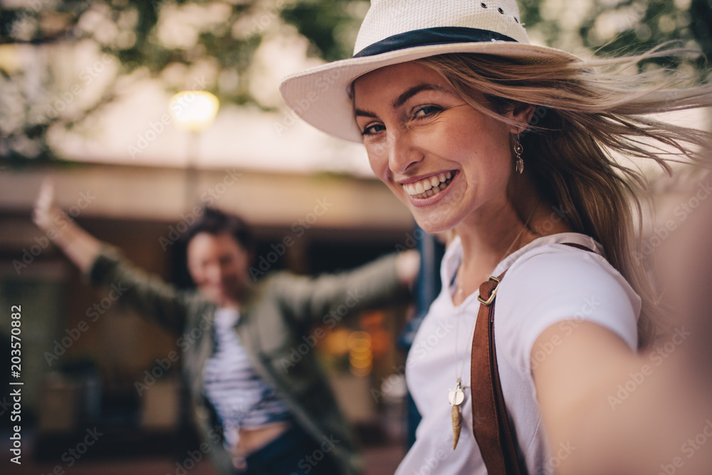 Woman talking selfie outdoors with a friends