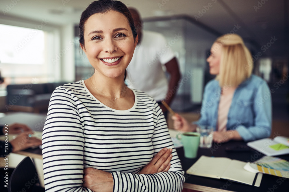 Young businesswoman smiling while sitting with colleagues in an