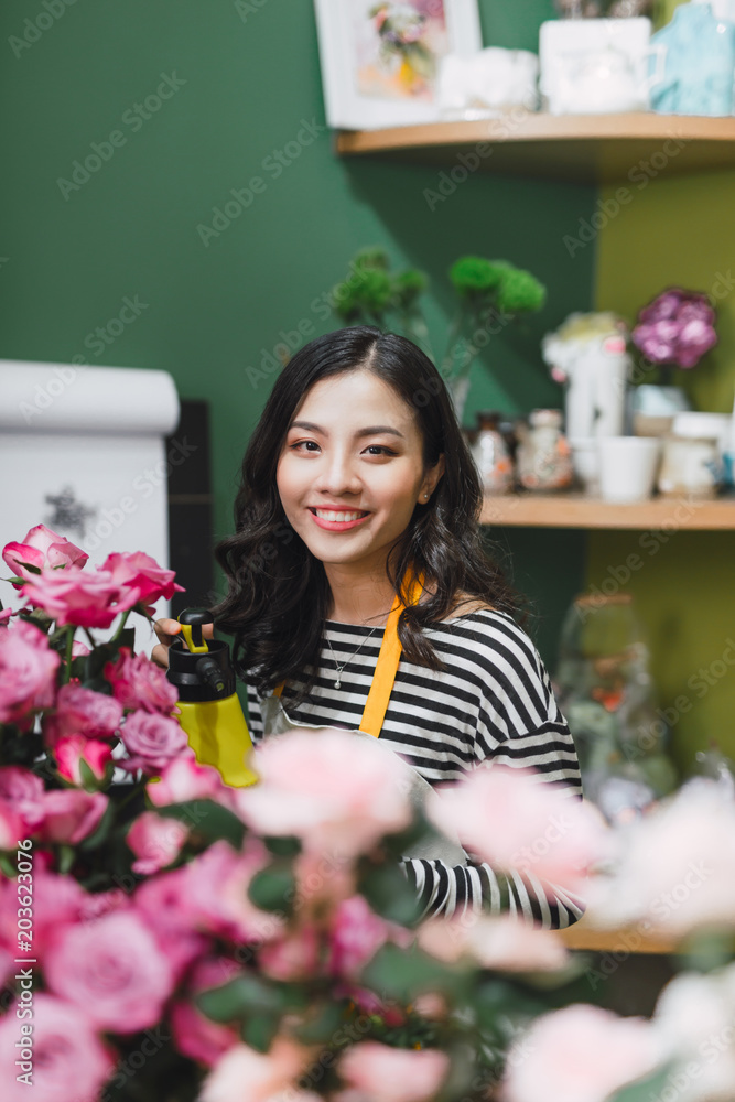 漂亮的年轻花匠在花店里拿着花束