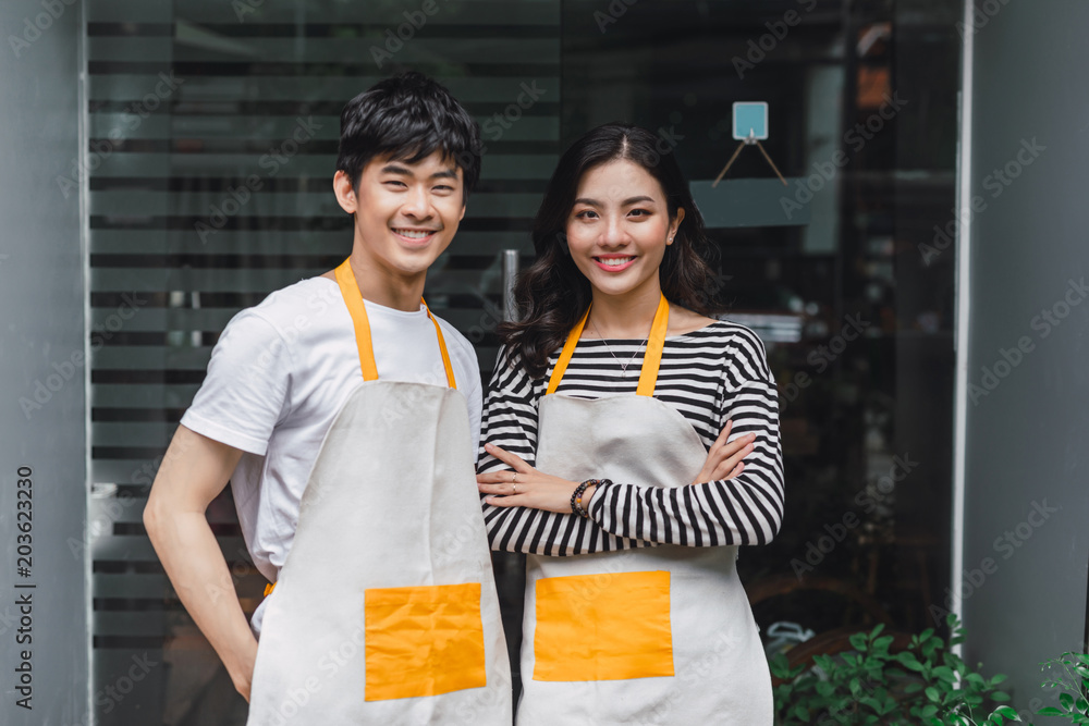 两个年轻的花商站在花店里，手里拿着一束花