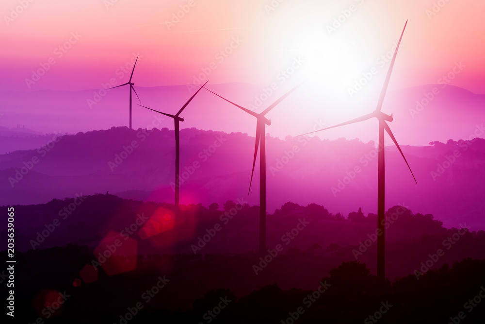 Wind turbines silhouette on mountains at sunset.