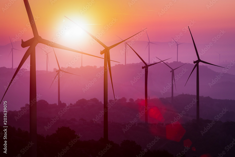 Wind turbines silhouette on mountains at sunset.