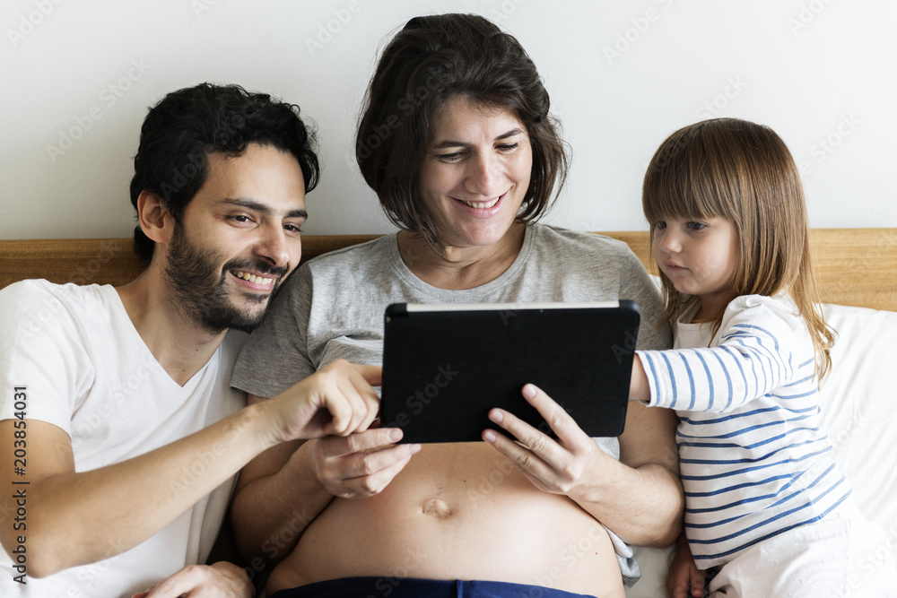 Pregnant family spending time together using a digital tablet