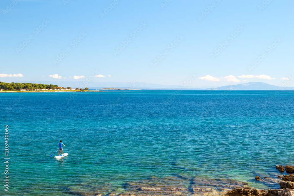 Man on SUP. Stand Up Paddling. Blue Sea Water. Floating Sup Board. Summer Vacation and Outdoor Sport