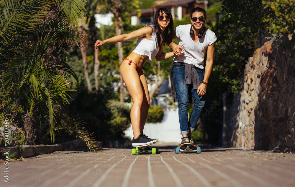 Happy couple riding on skateboards on vacation