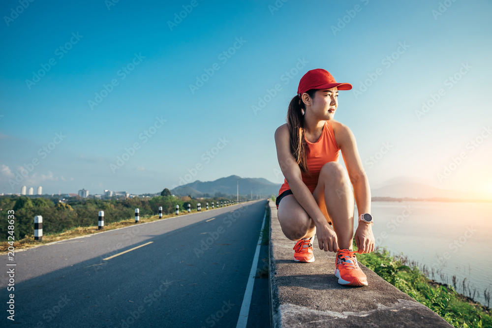 一名亚洲女运动员在水泥路上慢跑，她正在温暖自己的身体，缓解自己的紧张情绪