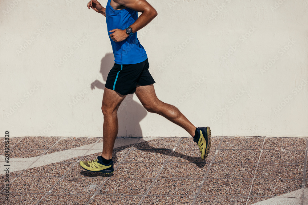 Athletic man jogging outdoors on sidewalk