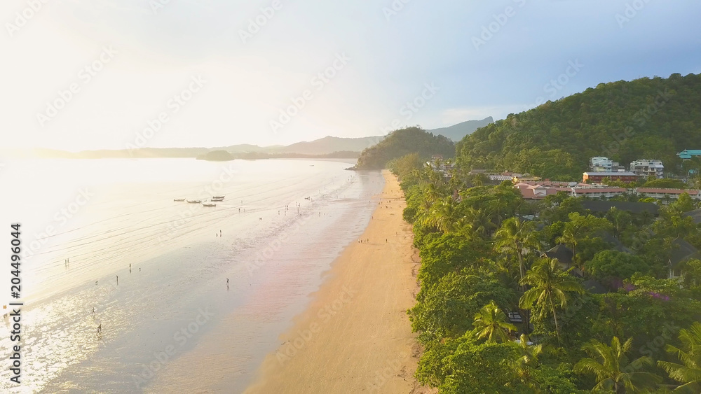 航空：沿着热带沙滩飞行，游客们享受假期。