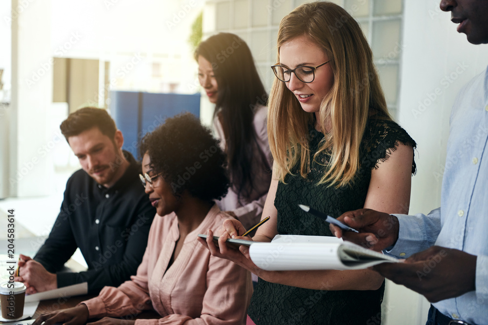 Smiling colleagues comparing notes together in a modern office