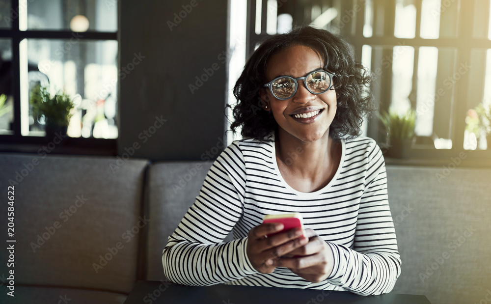 Smiling young African woman reading messages on her cellphone