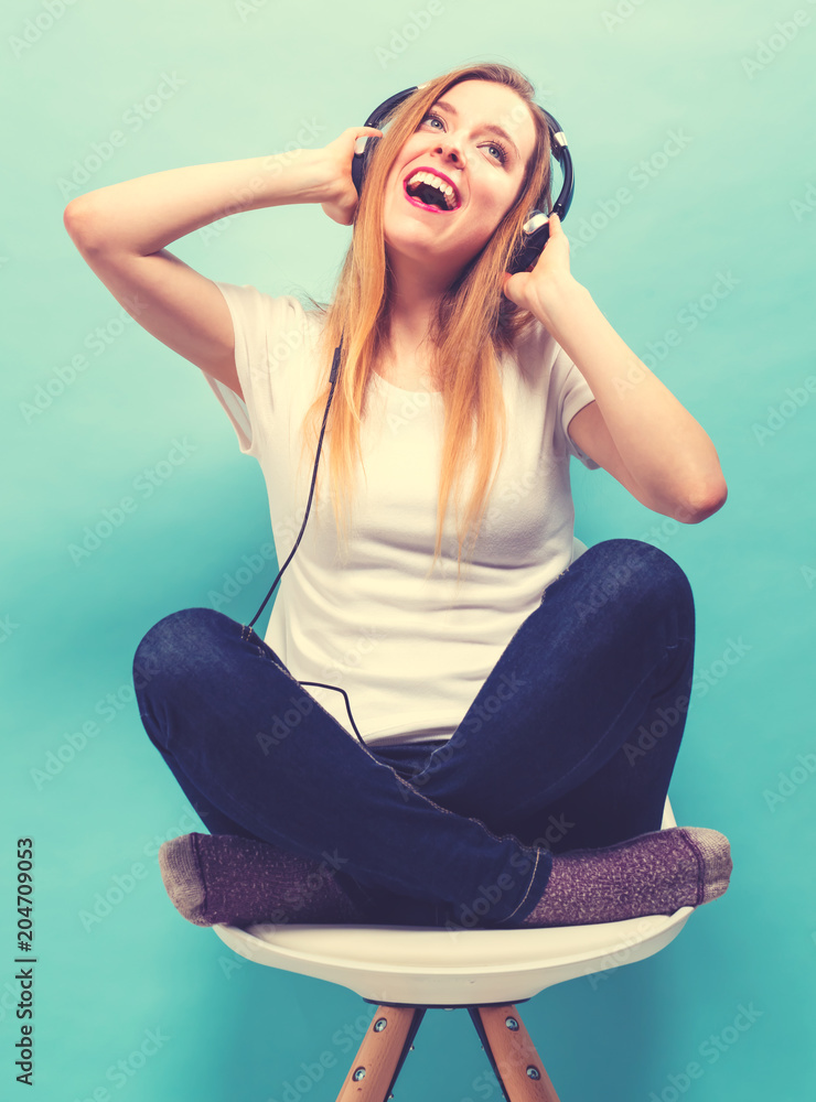 Happy young woman with headphones sitting in a chair