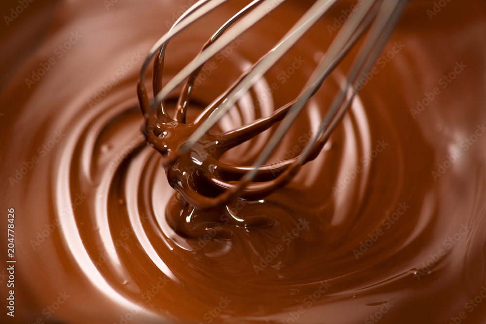 Chocolate. Mixing melted dark chocolate with a whisk. Closeup of liquid hot chocolate swirl. Confect