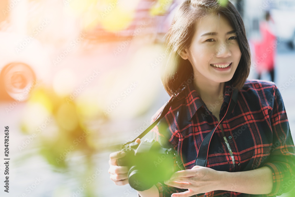 美丽的旅行者亚洲女人微笑着，带着相机在街头人行道上度假