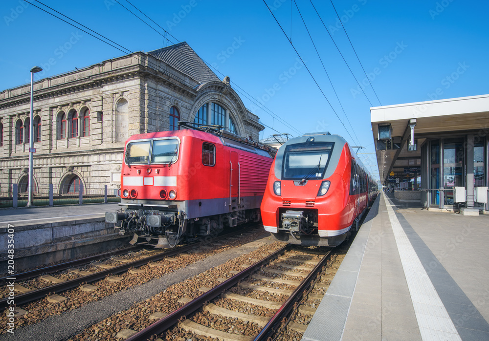 High speed train and old train on the railway station at sunset. Nuremberg, Germany. Modern intercit