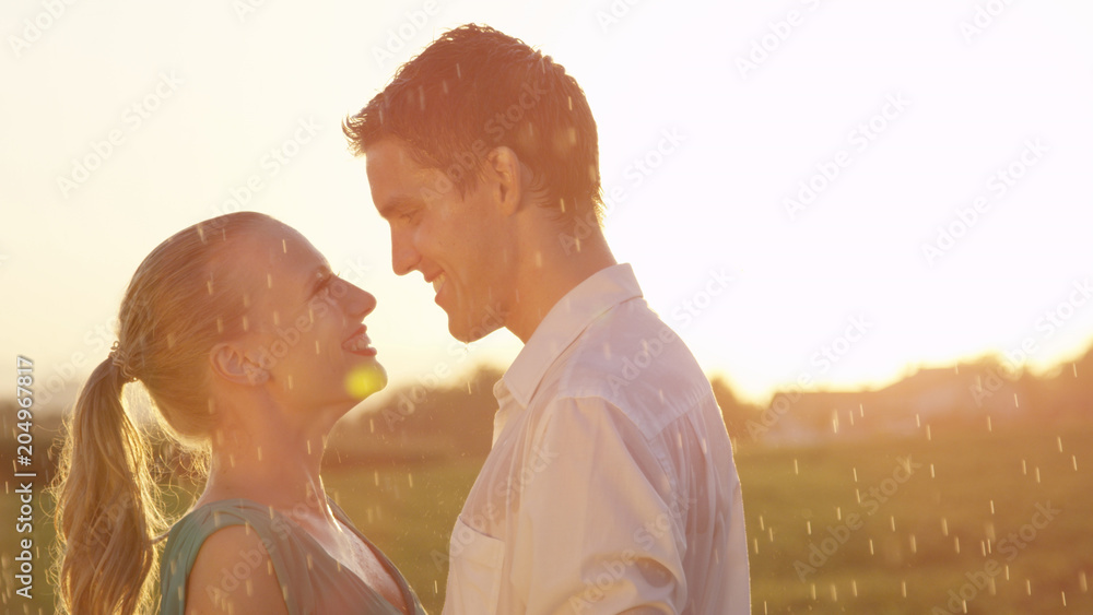 CLOSE UP: Young woman and man madly in love hold each other tight at sunset.