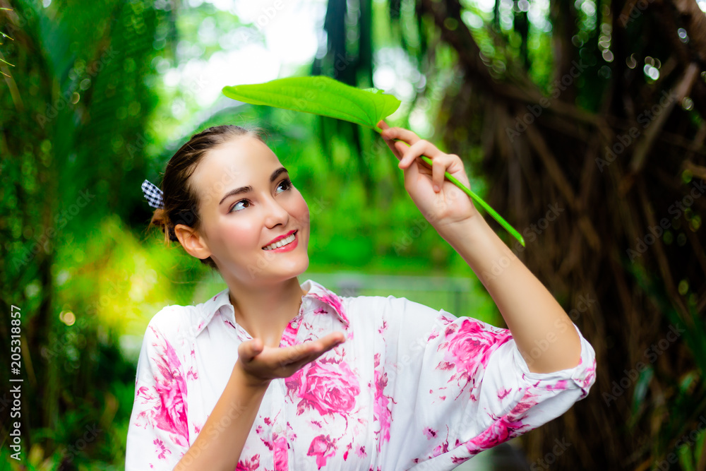 Gorgeous beautiful woman hold a leaf for closing her head when it’s raining. It’s rainy day. Charmin