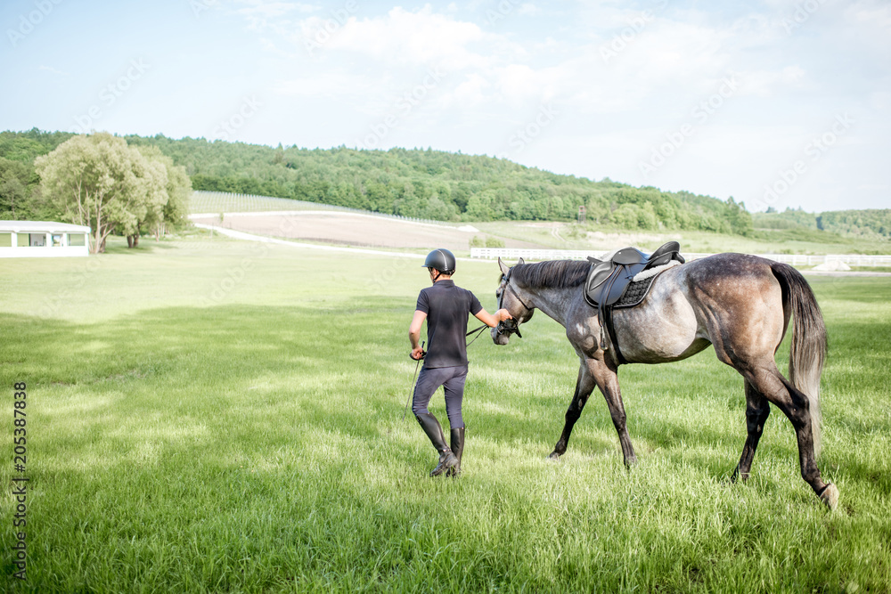 Horse rider leading a horse on the beautiful green field