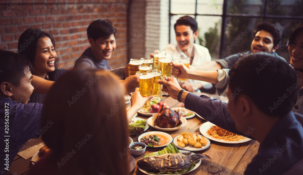 亚洲人正在庆祝节日，他们碰杯啤酒，晚餐快乐