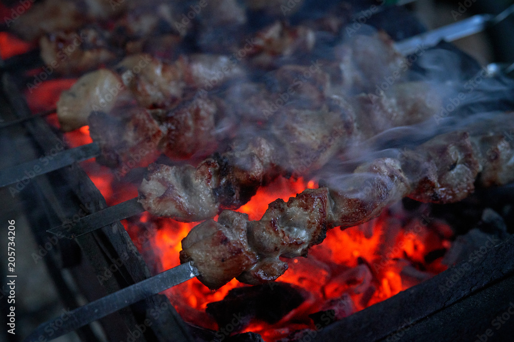 Shashlik preparing on a barbecue grill over charcoal. Pieces of meat on skewers. Shish kebab prepare