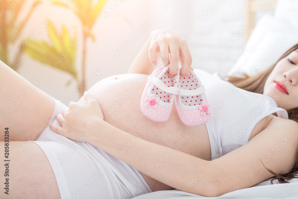 pregnant woman holding baby shoes