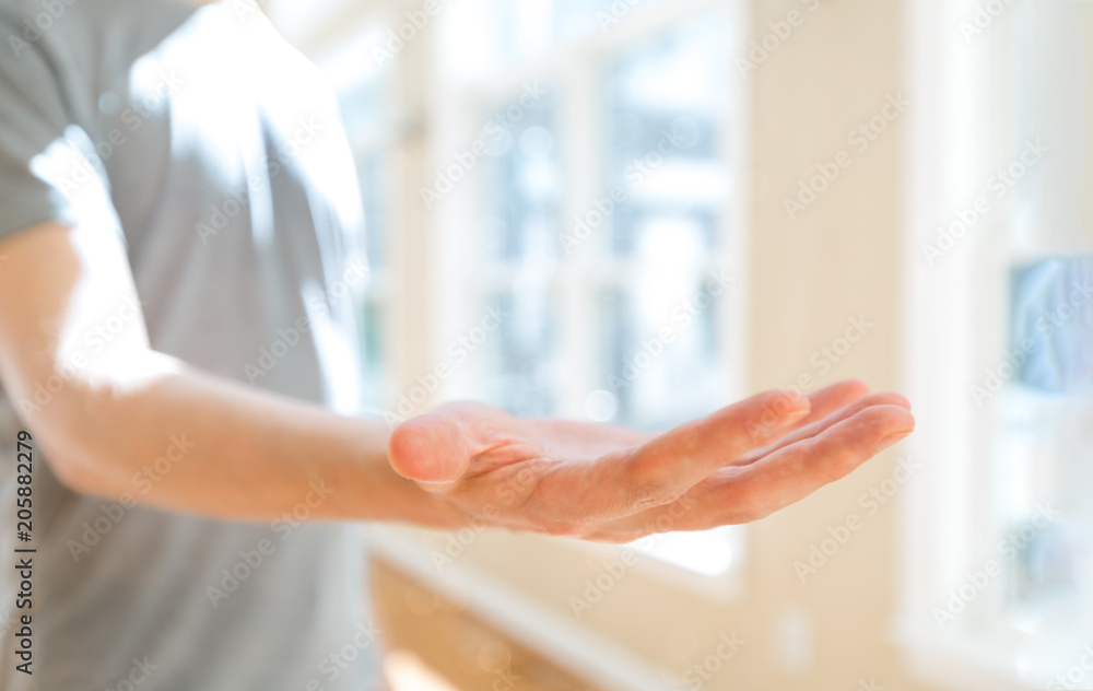 Man holding his hand out and showing something in a bright room