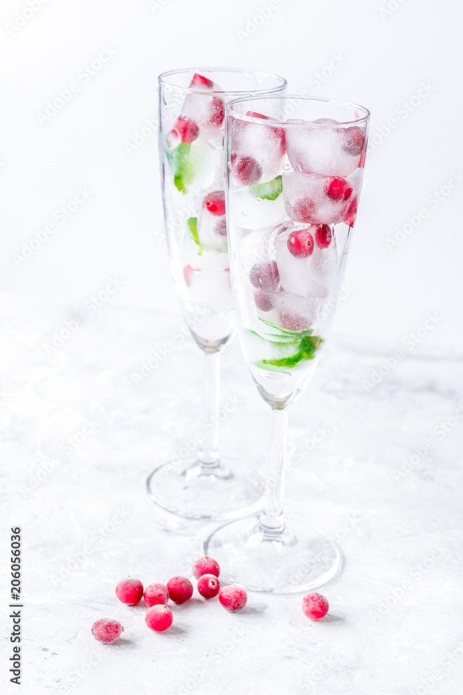 ice cubes with red berries and mint in glasses on white backgrou