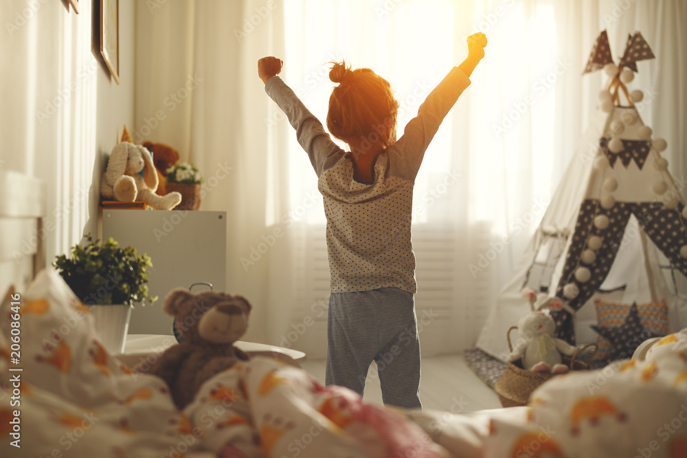 child girl wakes up  and stretches in morning in bed and stretches