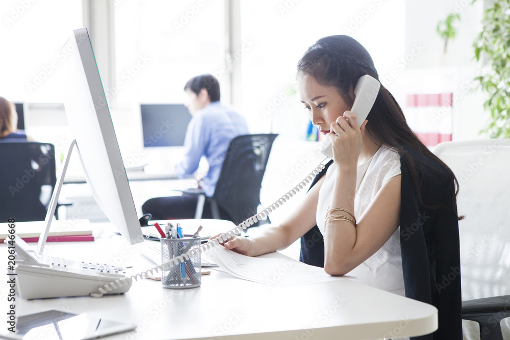 女性はオフィスで電話を受けている