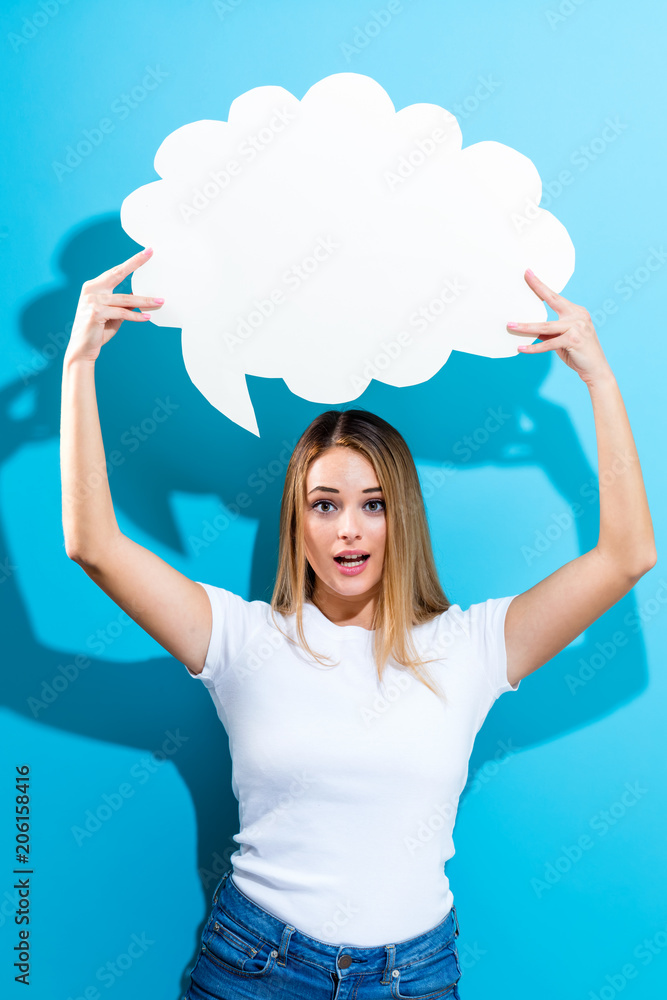 Young woman holding a speech bubble on a blue background