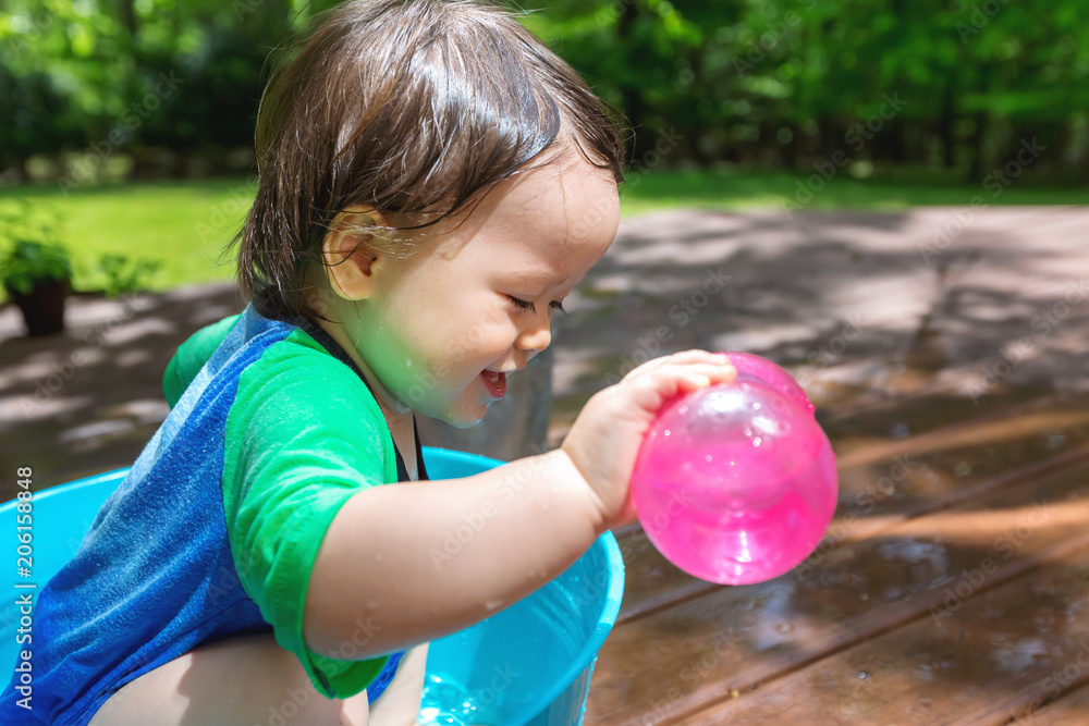 Young toddler boy playing with water outside