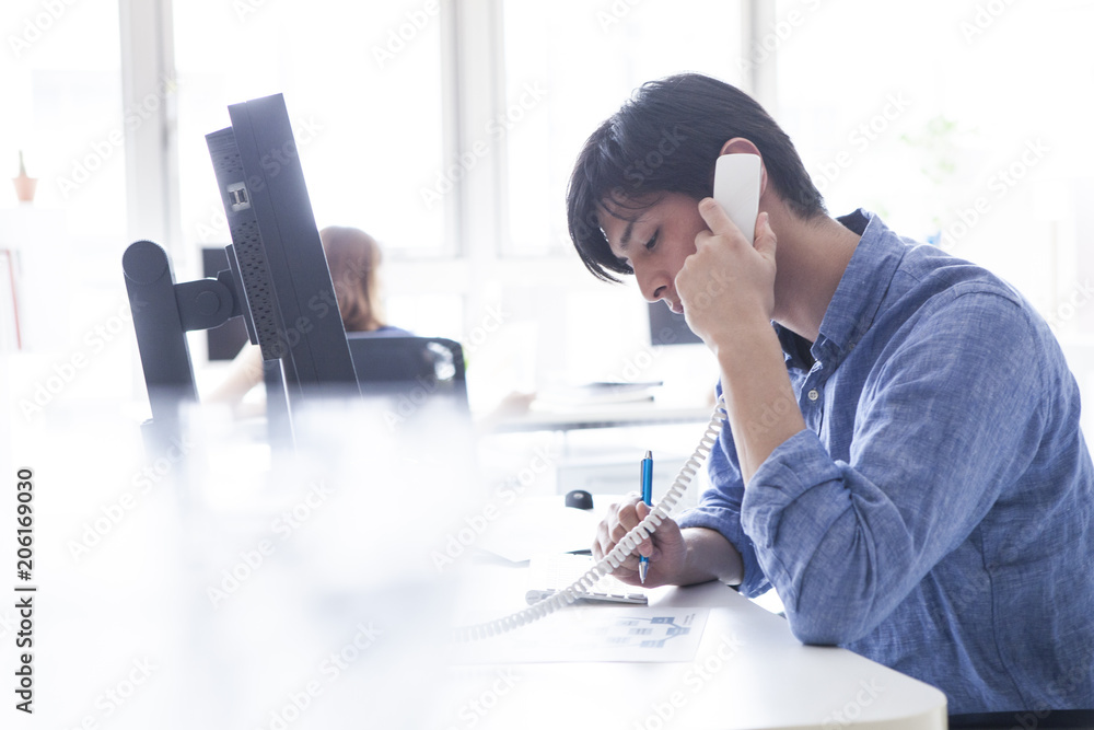 男性はオフィスでクライアントと電話している