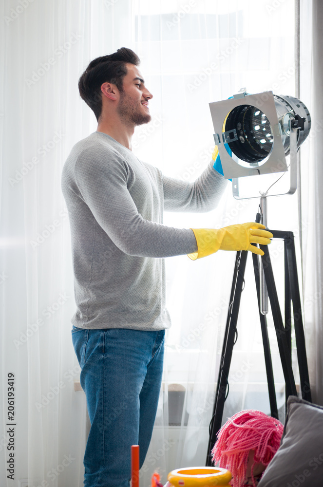 Handsome man in yellow gloves cleaning his flat