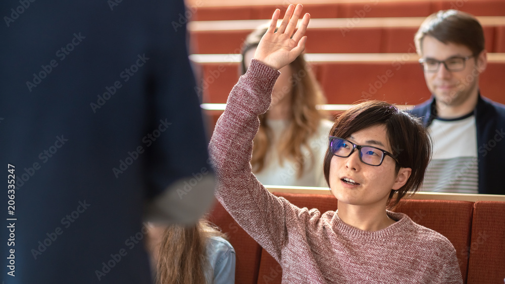 课堂上聪明的亚洲学生举手向讲师提问。多民族