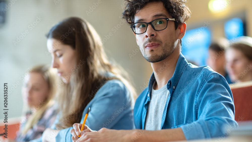 英俊聪明的西班牙裔男子在满是多民族学生的教室里听讲座。S