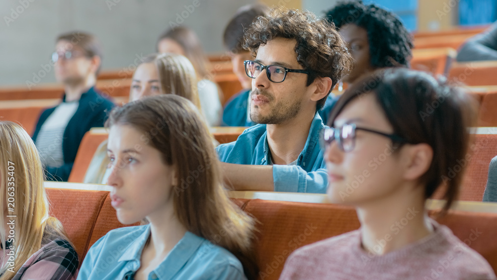 英俊聪明的西班牙裔男子在满是多民族学生的教室里听讲座。S