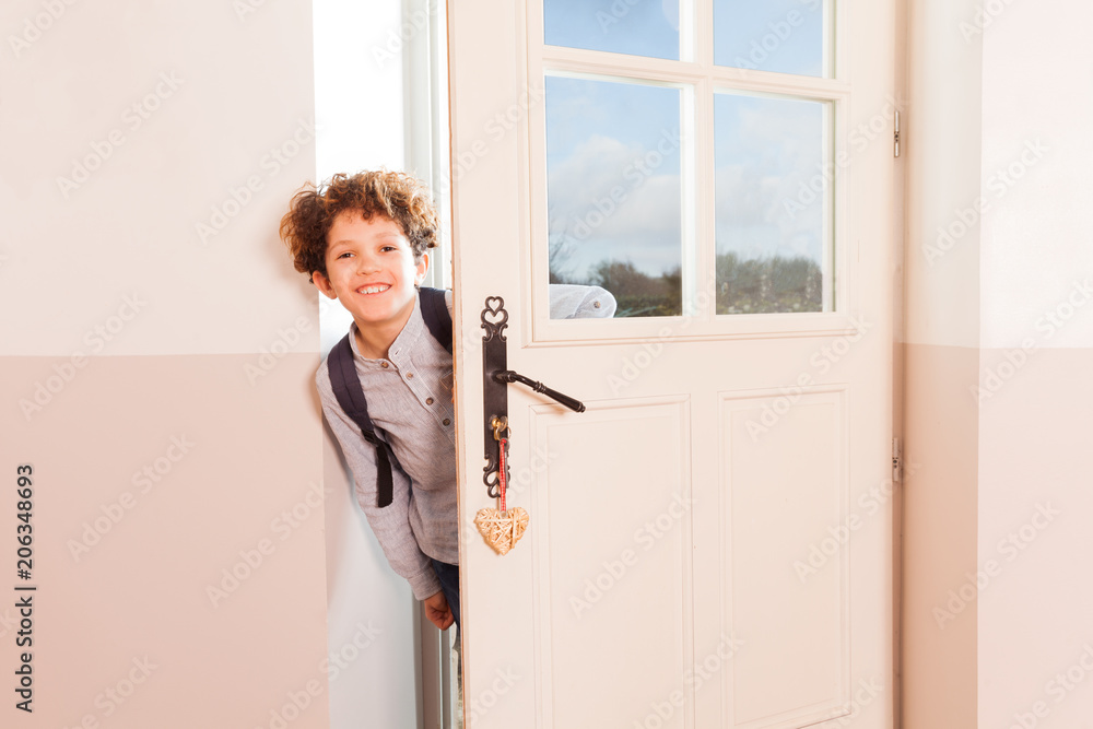 Happy schoolboy looking through the doorway