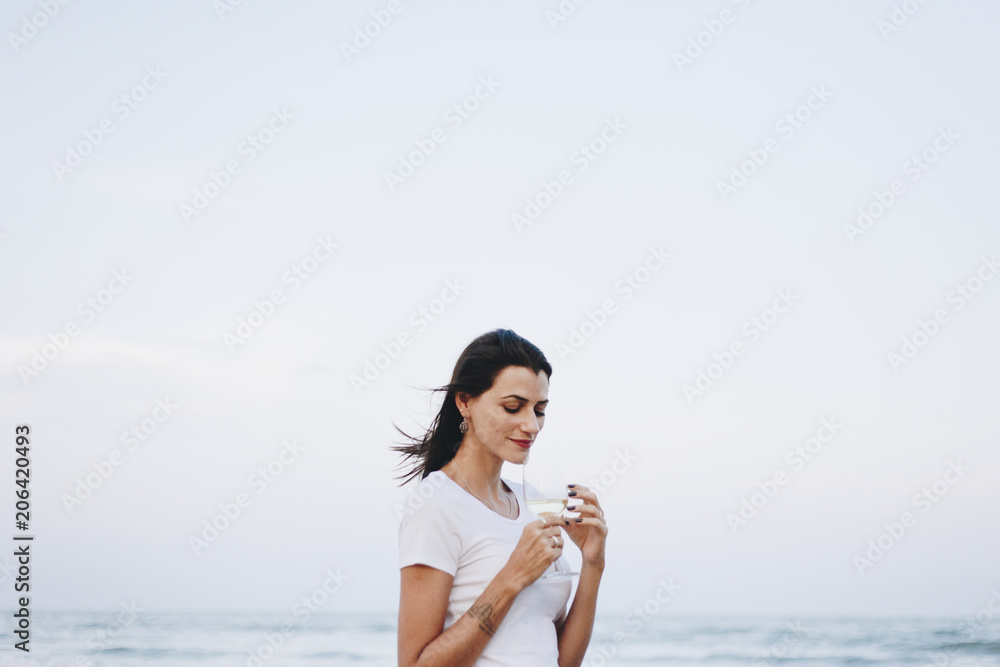 在海滩边喝一杯葡萄酒的女人