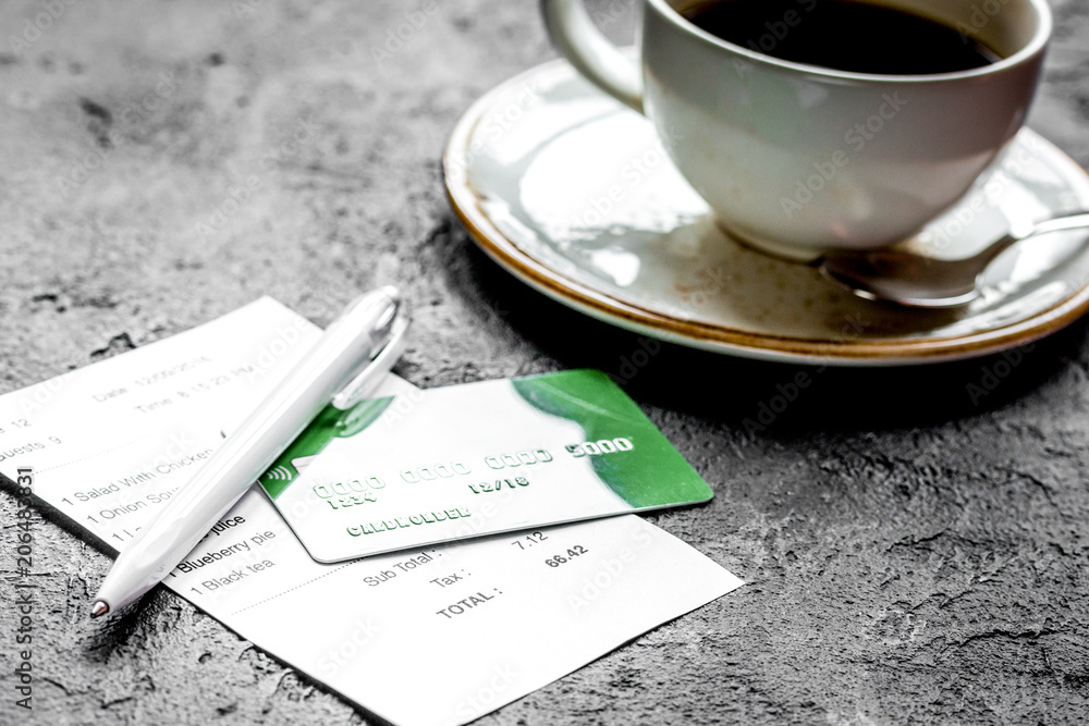 restaurant bill, card and coffee on dark table background