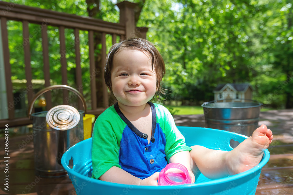 Young toddler boy playing with water outside